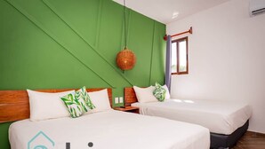 A double room with two beds, a green accent wall, a hanging basket, and a window with curtains. - Ideal room in a central area (Cancún)