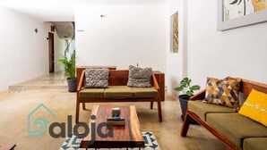 A modern living room with a sofa, a coffee table, and a potted plant. - Ideal room in a central area (Cancún)