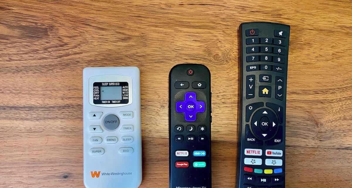 Three remote controls on a wooden surface.