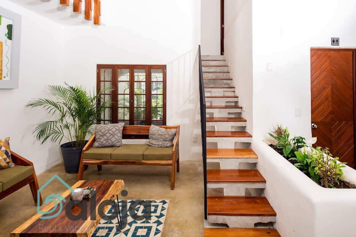 Un salon moderne avec un canapé, une table basse et un escalier menant à l’étage supérieur.