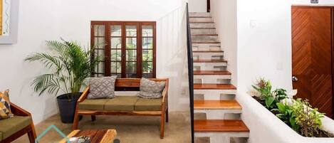 A modern living room with a sofa, a coffee table, and a staircase leading to an upper floor.