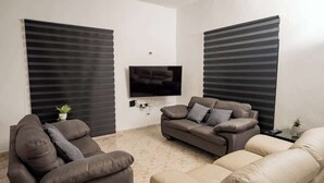 A living room with a flat-screen TV, two sofas, and a coffee table. - Villa for groups in excellent location (Playa del Carmen)
