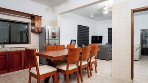 A modern kitchen with a dining area, featuring a large table and chairs, a refrigerator, and a television. - Villa for groups in excellent location (Playa del Carmen)