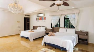 A hotel room with two beds, a chandelier, ceiling fan, and a large window with curtains.