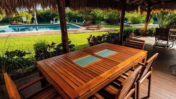 A wooden deck with a pool, lounge chairs, and a table with chairs.