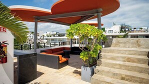 A rooftop terrace with outdoor seating, a covered area, and steps leading to a higher level. - Magnificent 2 blocks from the beach and 5th Ave. (Playa del Carmen)