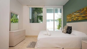 A bedroom with a bed, a dresser, a large window, and a painting on the wall. - Magnificent 2 blocks from the beach and 5th Ave. (Playa del Carmen)