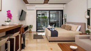 A modern living room with a sofa, a coffee table, a TV, and a desk with chairs. - Playa del Carmen Apartment: Rooftop Pool, City Views (Playa del Carmen)