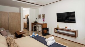 A hotel room with a bed, a TV, a desk, and a kitchenette. - Playa del Carmen Apartment: Rooftop Pool, City Views (Playa del Carmen)