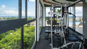 A gym with exercise equipment and a view of the ocean. - Playa del Carmen Apartment: Rooftop Pool, City Views (Playa del Carmen)