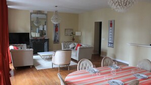 Un salon avec une cheminée, une table à manger dressée pour quatre personnes et un téléviseur en arrière-plan.