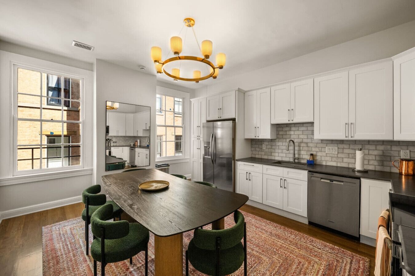 A modern kitchen with white cabinets, a central island, and a stainless steel refrigerator.