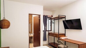 Un dormitorio con cama, un escritorio con silla, un televisor y un armario.