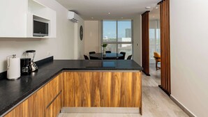 Une cuisine moderne avec des meubles en bois, un plan de travail noir et un four à micro-ondes encastré.