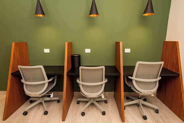 Une salle de conférence équipée de trois bureaux, chacun avec une chaise de bureau blanche et une lampe noire.