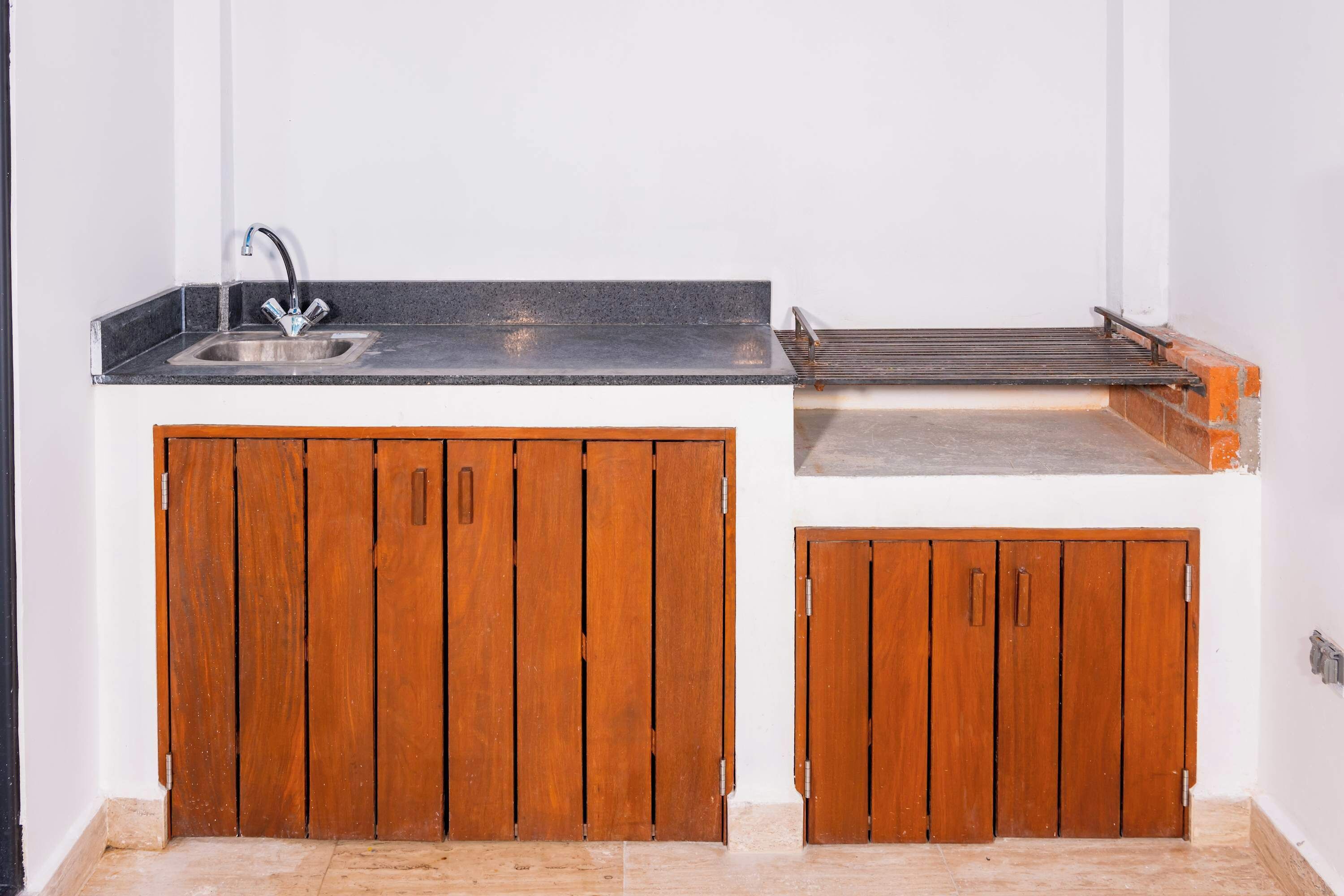 A compact kitchen with a sink, a drying rack, and wooden cabinets.