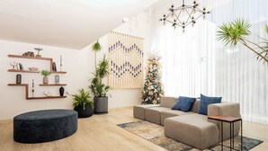 A modern living room with a sectional sofa, a round ottoman, and a coffee table. There are shelves with decorative items and a large wall hanging. - Charm and modernity together (Cancún)