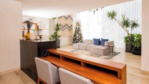 A modern living room with a wooden coffee table, grey sofas, and a small kitchen area with a built-in oven. - Charm and modernity together (Cancún)