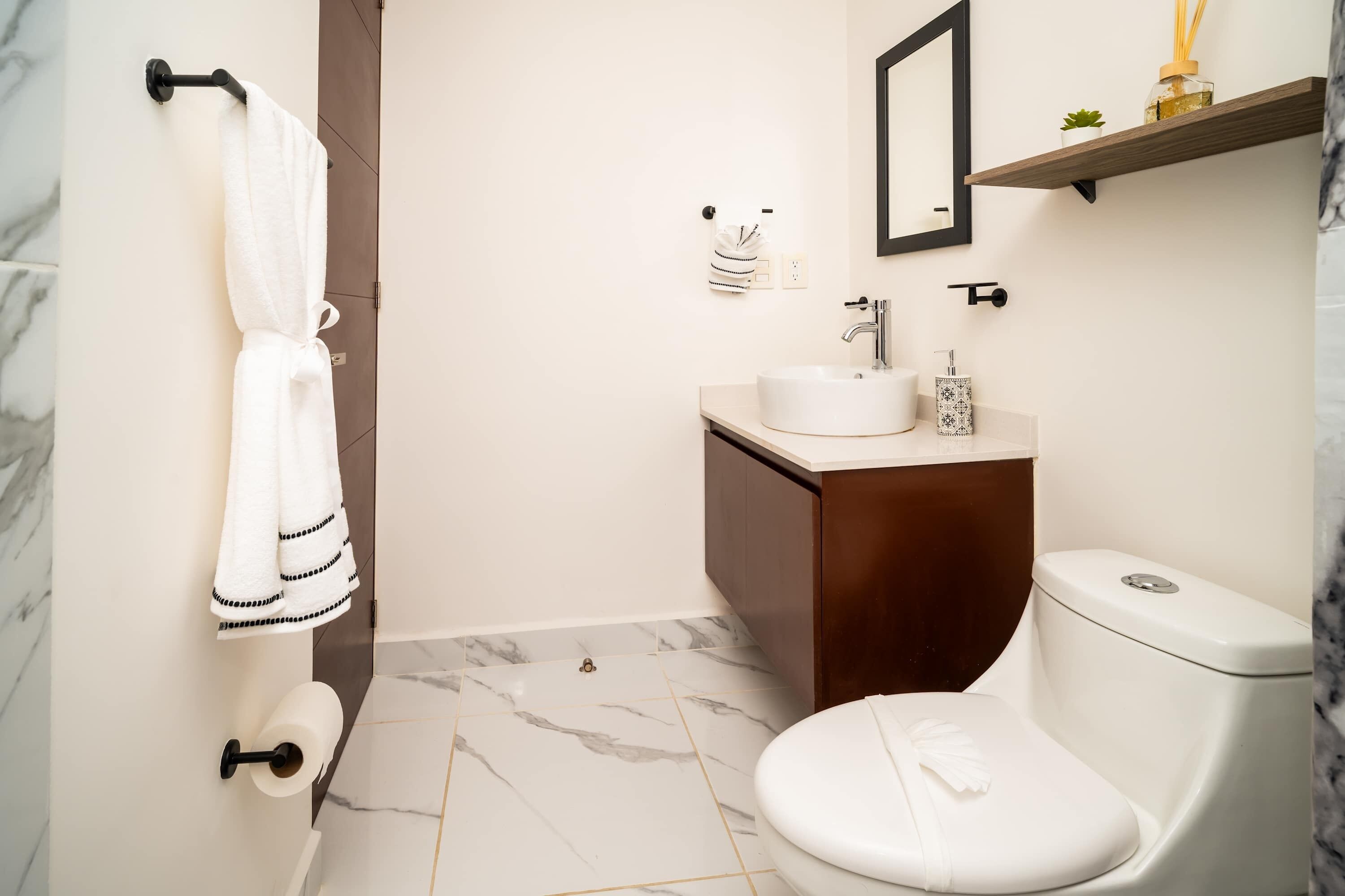 Une salle de bain équipée de toilettes, d’un lavabo et d’un porte-serviettes.