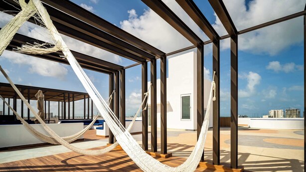 Un hamac sur une terrasse en bois, avec vue sur les gratte-ciel de la ville.