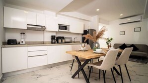 Une cuisine moderne avec des meubles blancs, une table à manger en bois et un réfrigérateur noir.