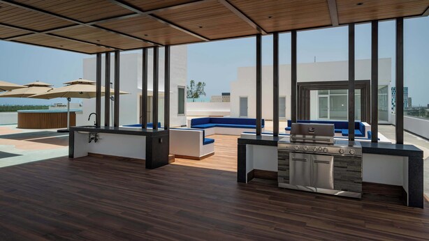 A spacious outdoor area with a modern kitchen, seating, and large windows. - Unique Studio at the Entrance of the Hotel Zone (Cancún)