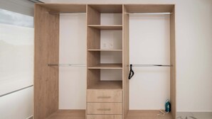 A wooden wardrobe with multiple compartments, including drawers and shelves, in a minimalist room. - Unique Studio at the Entrance of the Hotel Zone (Cancún)