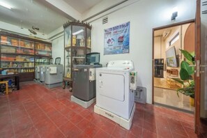 A laundry room with industrial washing machines, a glass cabinet, and a poster on the wall. - Swing By (Bangkok)