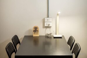 A conference table with a power outlet, a lamp, and a Wi-Fi symbol on a stand. - Swing By (Bangkok)