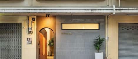 A hotel entrance with a gated driveway, a reception desk, and a potted plant.