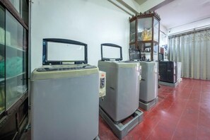 Une pièce comprenant trois gros appareils électroménagers, un meuble en bois et une fenêtre avec des rideaux.