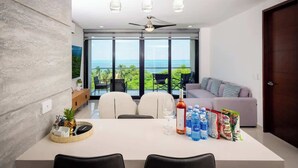 A modern dining area with a large table, chairs, and a view of the ocean. - Oceanview with Rooftop Pool in Playa Tortugas (Cancún)