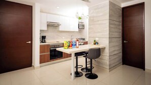 A modern kitchen with a white countertop, two black bar stools, and a microwave. - Oceanview with Rooftop Pool in Playa Tortugas (Cancún)