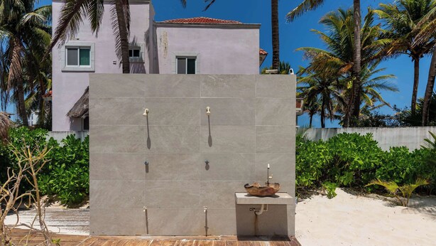 A modern outdoor bathroom with a stone wall, a wooden deck, and a sink. - Arenika suite Kala con vista al mar (Puerto Morelos)