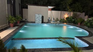 A swimming pool with a tiled edge, surrounded by potted plants and a wall with a built-in heater. - "Kanchan Kutir villa" A Serene Escape in the Heart of Udaipur" (Udaipur)