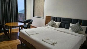 A hotel room with a large bed, a round wooden table, a chair, and a view of the outdoors through a balcony. - "Kanchan Kutir villa" A Serene Escape in the Heart of Udaipur" (Udaipur)