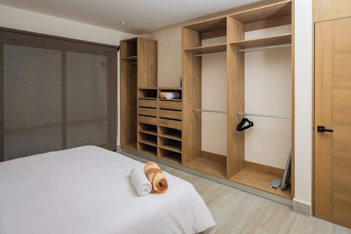 A hotel room with a bed, a large wardrobe with multiple compartments, and a small seating area.