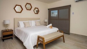 Un dormitorio con una cama, mesitas de noche y un ventanal grande.