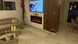 A modern living room with a flat-screen TV, a fireplace, and a sofa.