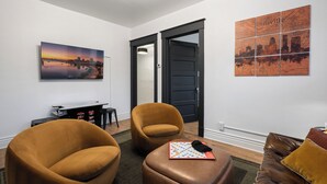 A modern living room with a large cityscape painting, a black door, and a brown leather sofa.