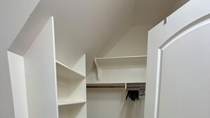 A walk-in closet with white shelving units and a gray trash bin. - Refined Carriage Apartment in Historic Hope Valley (Durham)