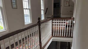 A multi-level staircase with white railings and wooden steps, leading to a balcony with a view of the outdoors. - Refined Carriage Apartment in Historic Hope Valley (Durham)