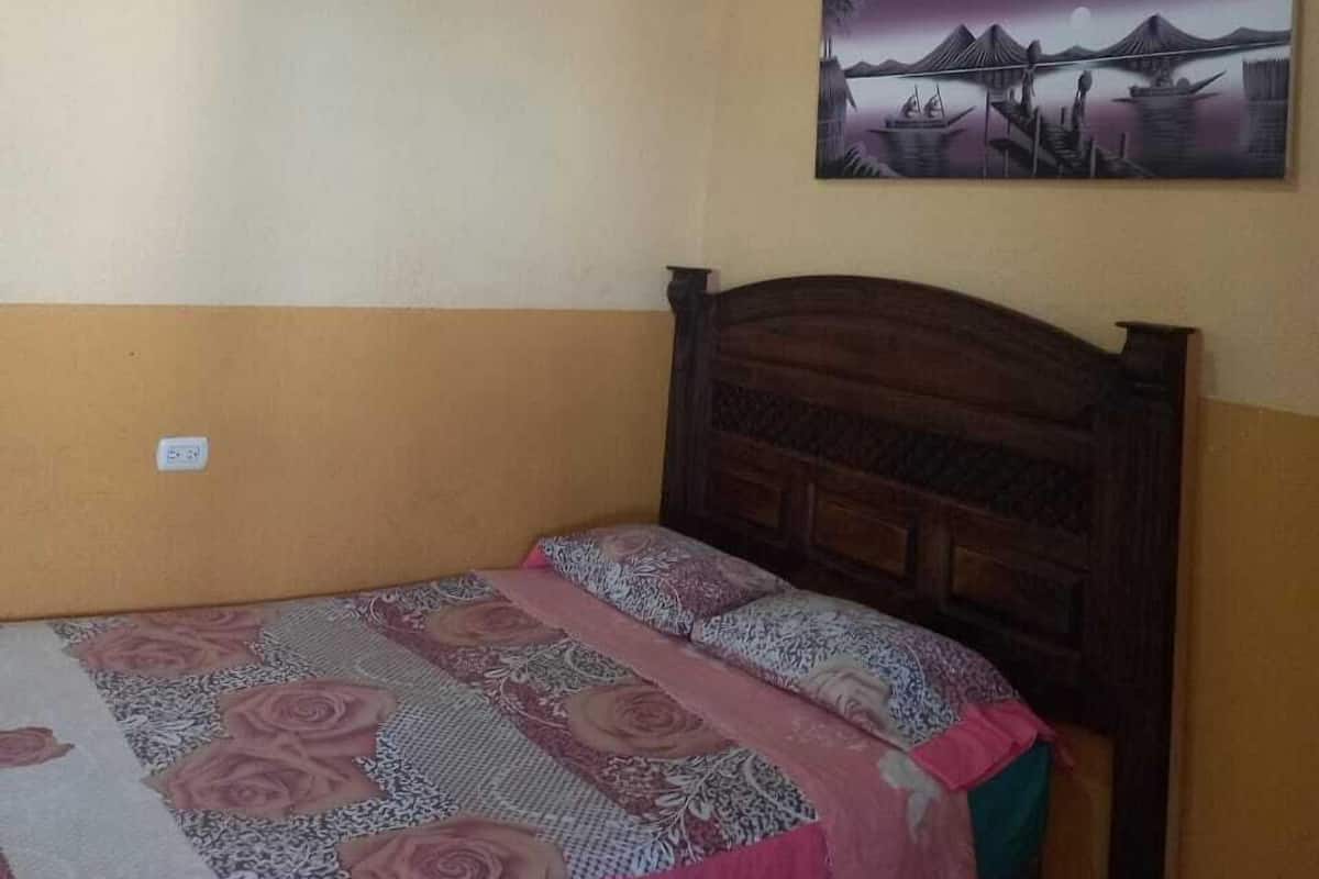 Une chambre à coucher avec un lit, un luminaire au plafond et un tableau accroché au mur.