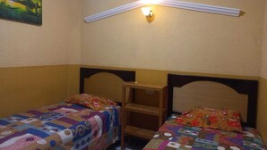 A room with two beds, a nightstand, a wall-mounted light, and a painting. - Hotel Peneleu (San Pedro La Laguna)