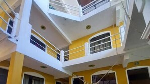 A multi-level building with yellow walls and white railings, featuring a checkered floor pattern. - Hotel Peneleu (San Pedro La Laguna)