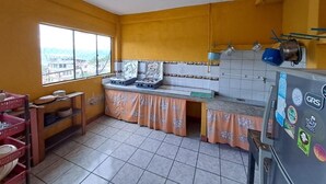 A kitchen with a window, tiled floor, and a refrigerator. - Hotel Peneleu (San Pedro La Laguna)