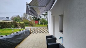 Un espace extérieur abrité, doté d’un mur en pierre, d’une clôture en treillis et de mobilier en rotin noir.