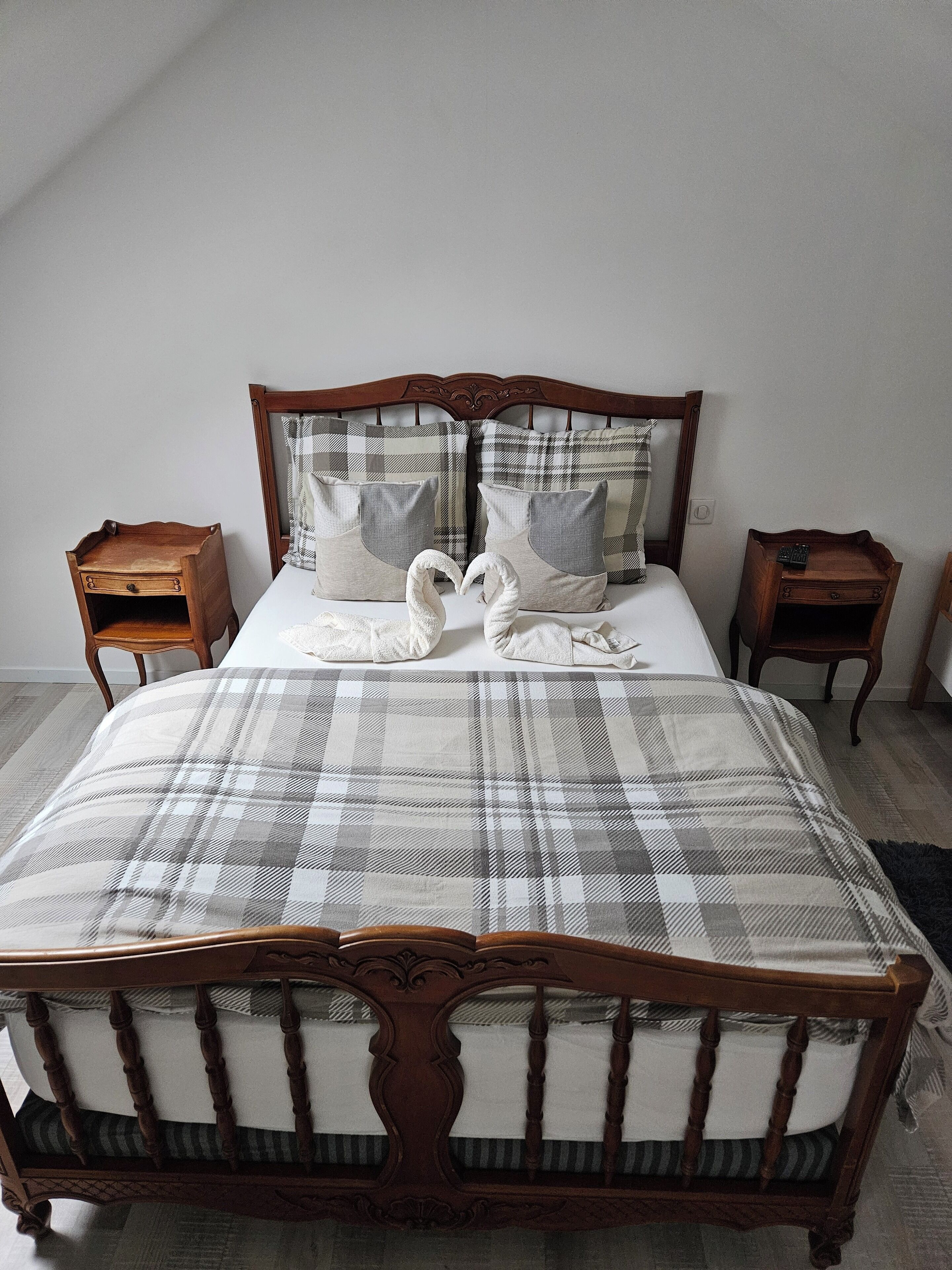 A bed with a plaid bedspread, two pillows, and two wooden nightstands.
