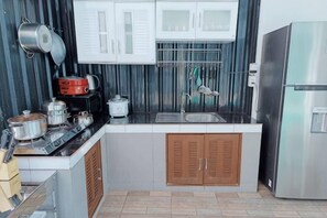 Una cocina compacta con estufa, pileta y alacenas.