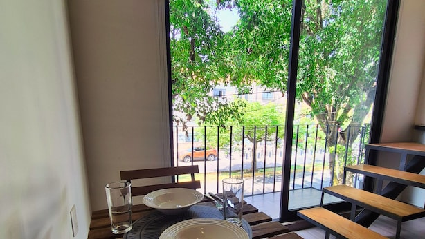A dining area with a table set for two, a glass of water, and a metal fork. - Lofts La Paz (Guadalajara)